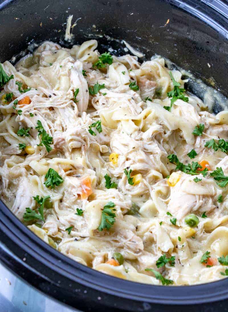 Chicken and noodles in slow cooker with parsley sprinkled on top