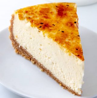Slice of cheesecake on white plate showing caramelized topping