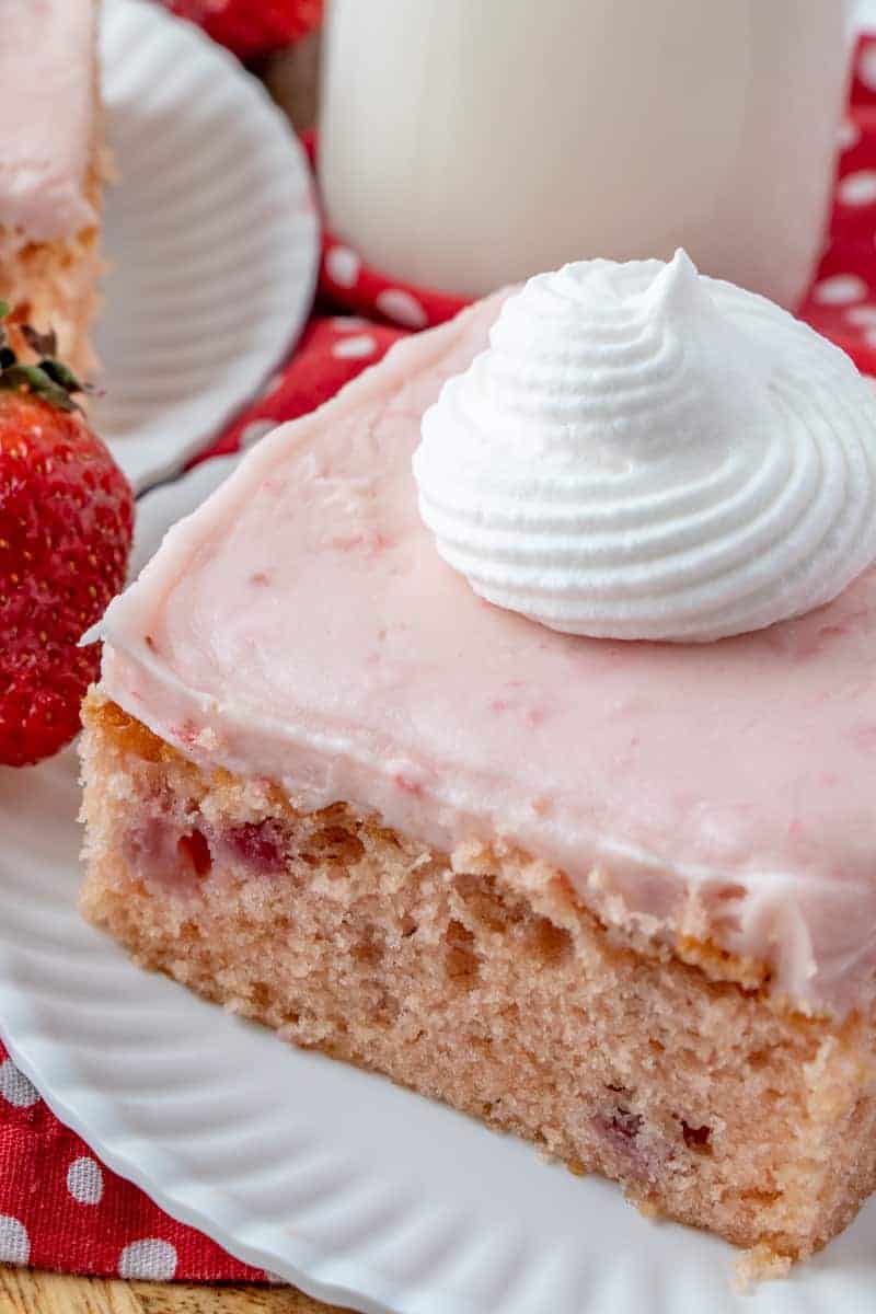 Strawberry Cake on plate up close from angle with whipped cream on top
