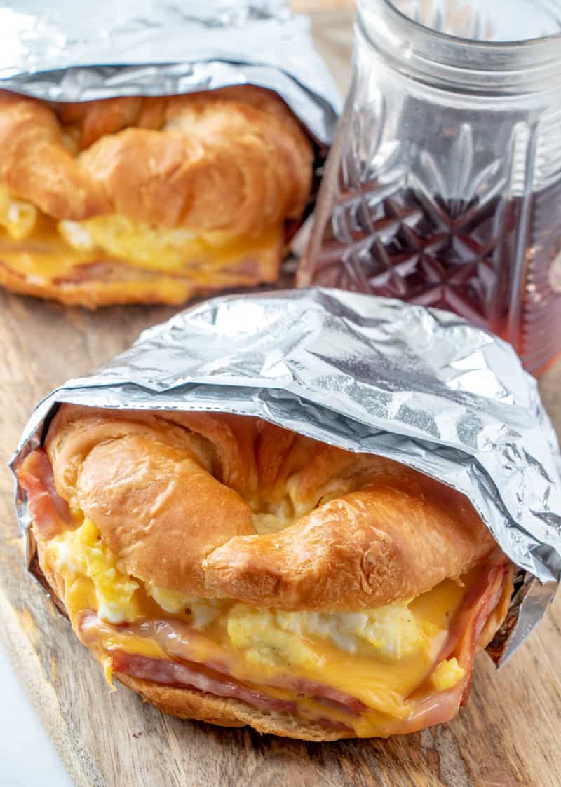 Overhead shot of Croissant Breakfast Sandwiches with syrup in background