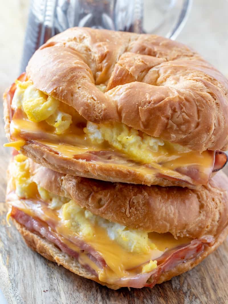 Dos sándwiches de desayuno de croissant fáciles apilados uno encima del otro