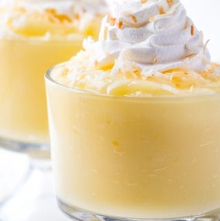 Coconut pudding in glass dish topped with whipped cream and toasted coconut