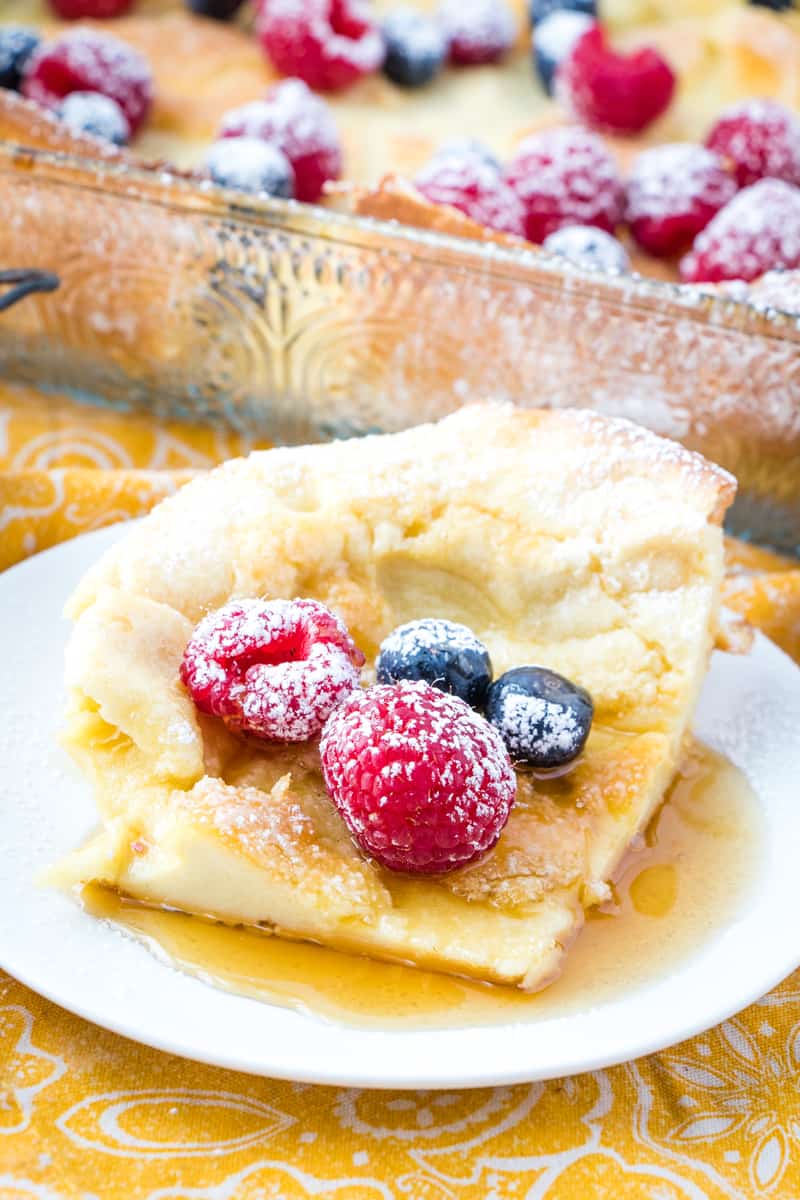 Close up of German pancakes sliced on plate with fruit and syrup
