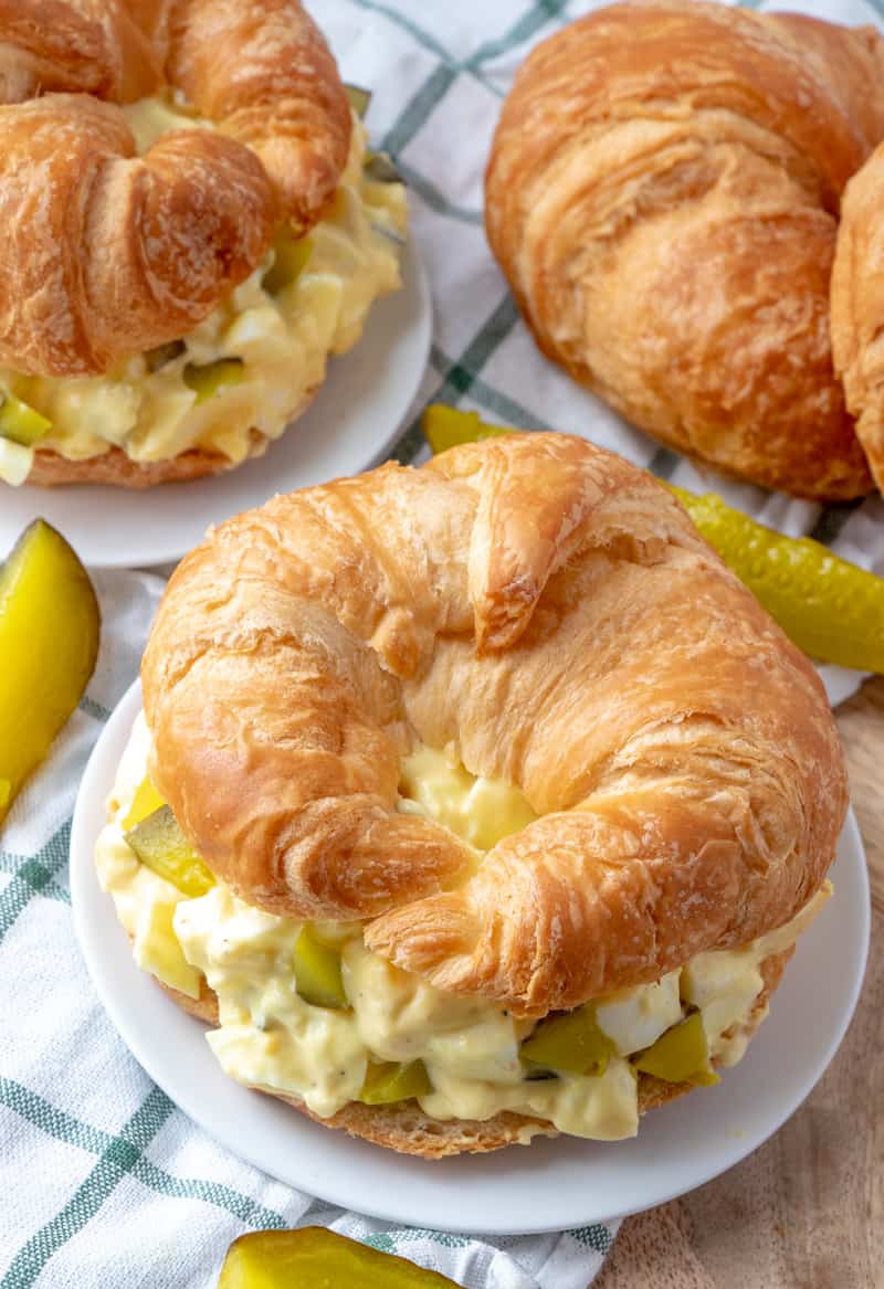 Overhead photo of egg salad recipe on plate with croissants in background