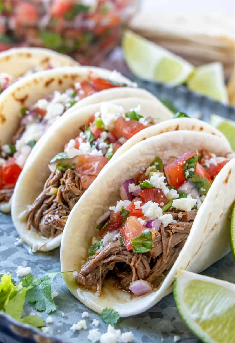 Close up photo of street tacos with pico, sauce and cheese
