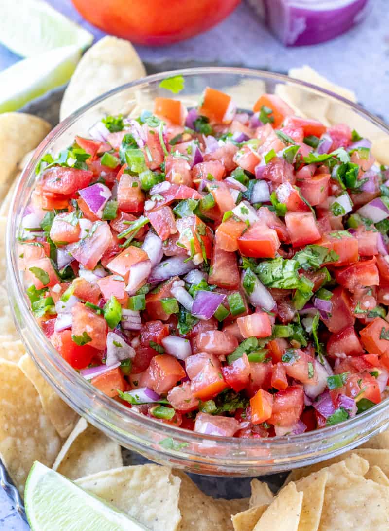 finished shot of pico de Gallo recipe in bowl with chips, limes and tomatoes