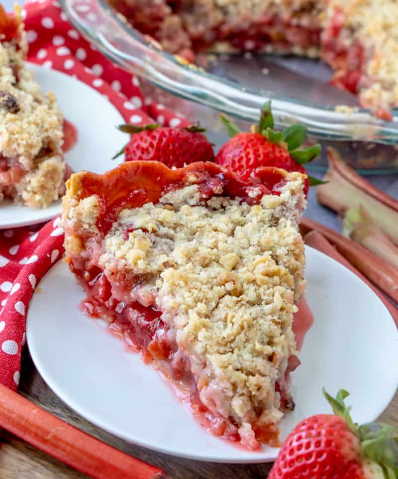 Strawberry Rhubarb Pie on white plate with strawberries in back