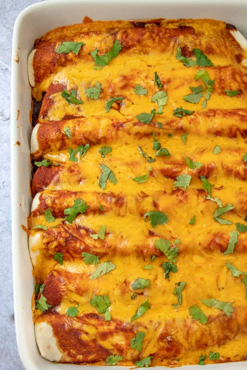 Ground been enchiladas rolled in pan after baking with melted cheese and cilantro