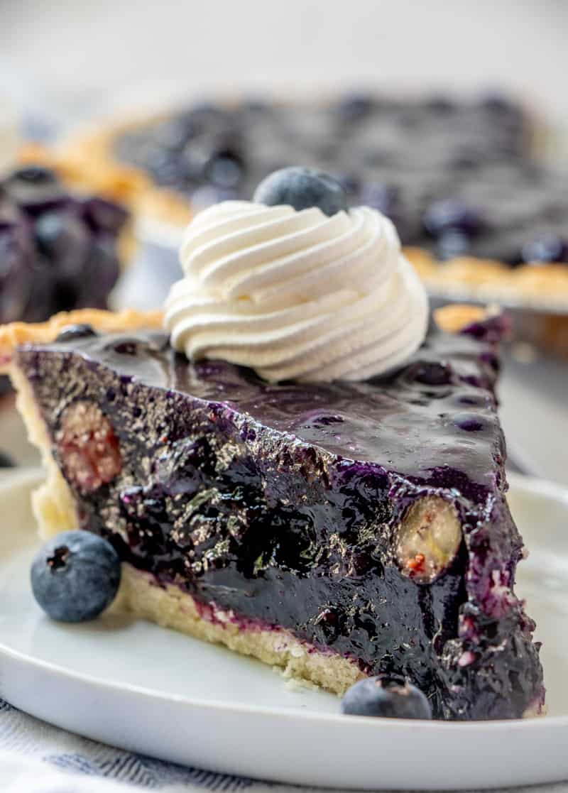 close up side shot of pie on plate with cut blueberries in pie