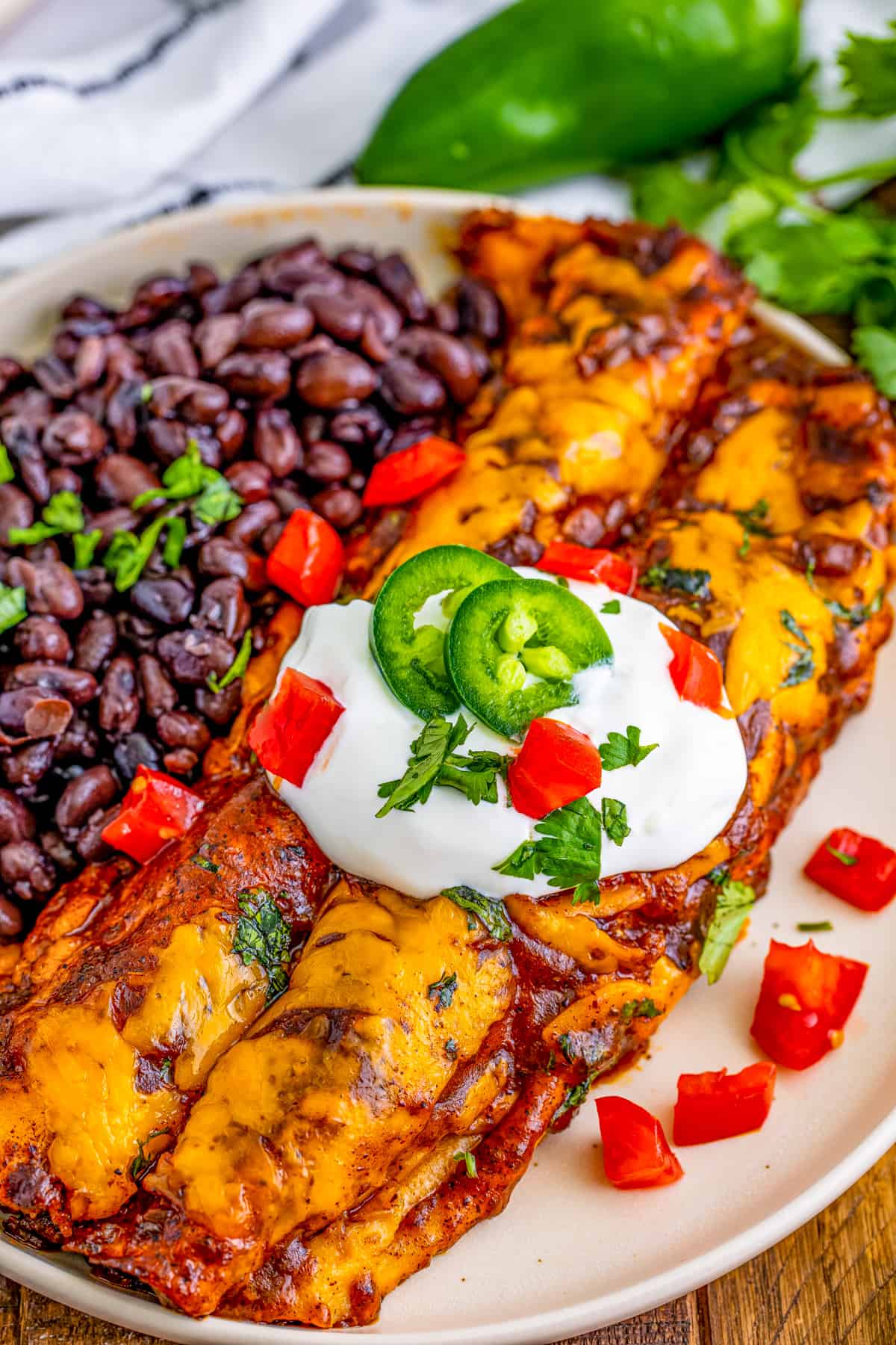 Overhead photo of two Enchiladas on white plate garnished and served with black beans.