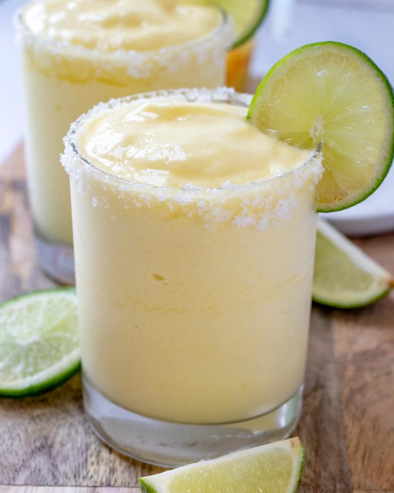 margaritas in glass with lime slice and limes around the glass