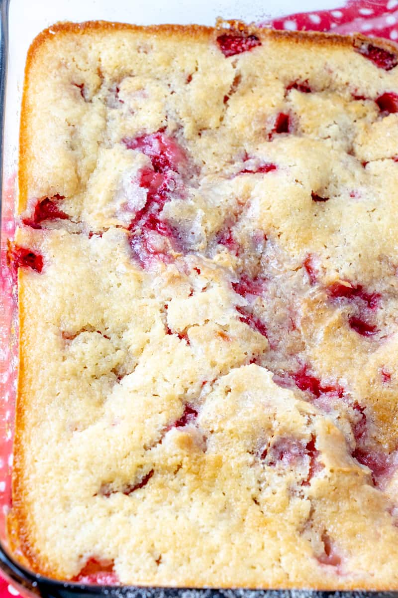 Sugar crusted top of cobbler after baked in pan with strawberries poking through