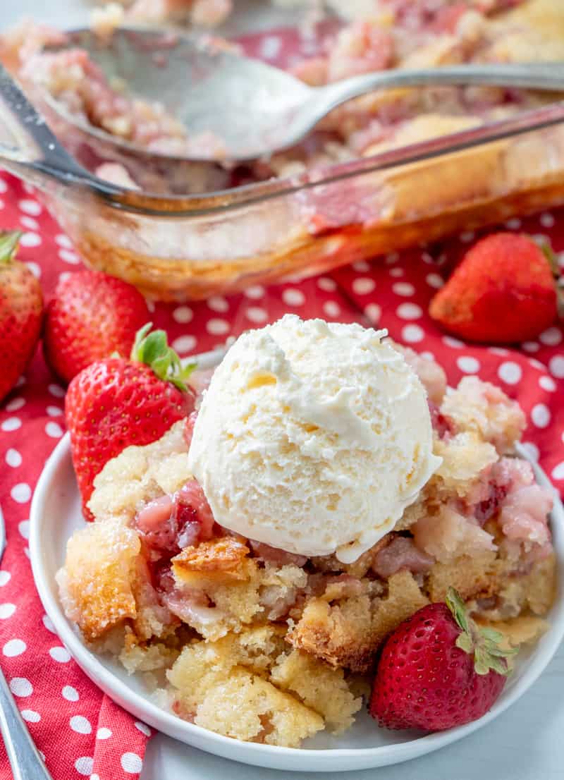 Cobbler on plate with scoop of ice cream and whole strawberries