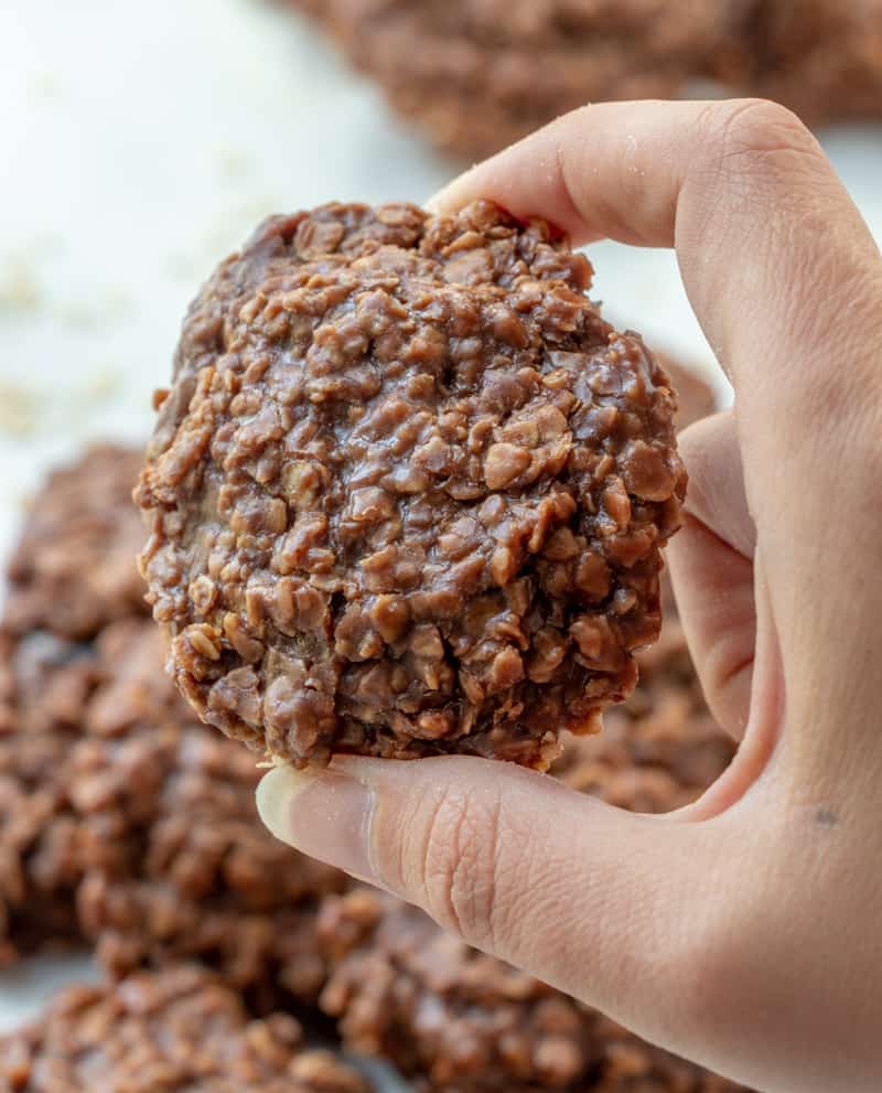Hand holding one easy no bake cookie showing off the chocolate and oats