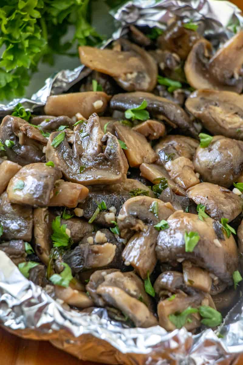 Up close photo of tender juicy mushrooms in tinfoil topped with parsley