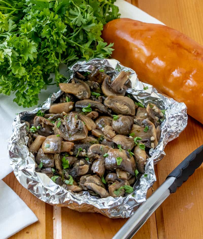 grilled mushrooms in tinfoil with parsley and read surrounding them