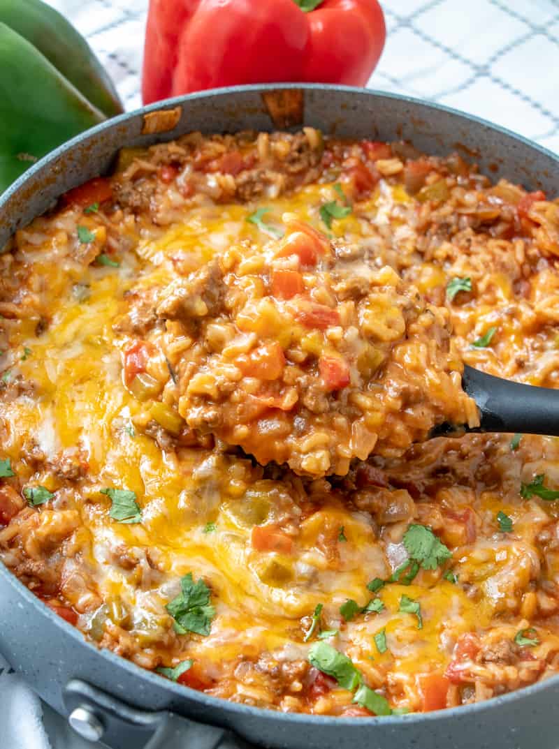 stuffed pepper casserole in pan with cheese melted on top and a spoon holding some to serve