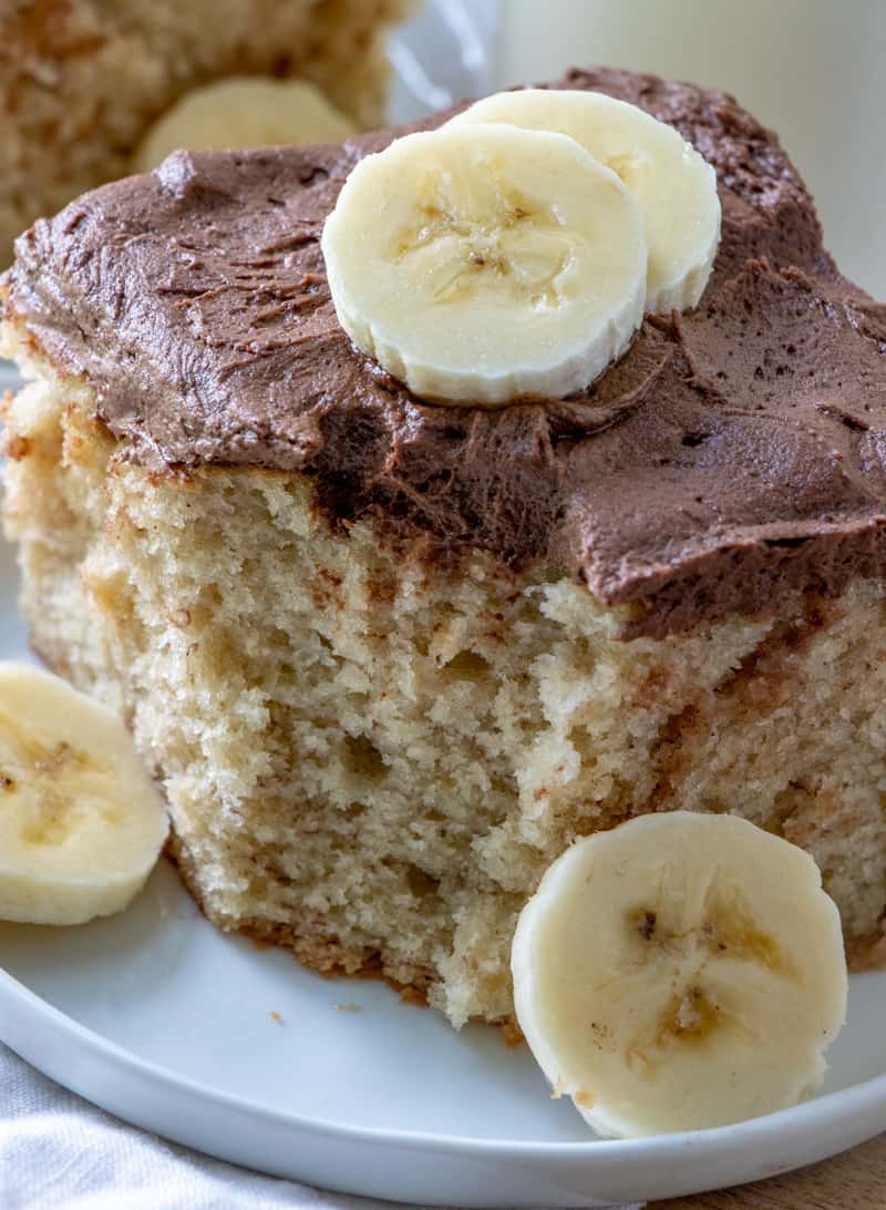 Bite taken out of slice of banana cake with banana slices on cake and plate