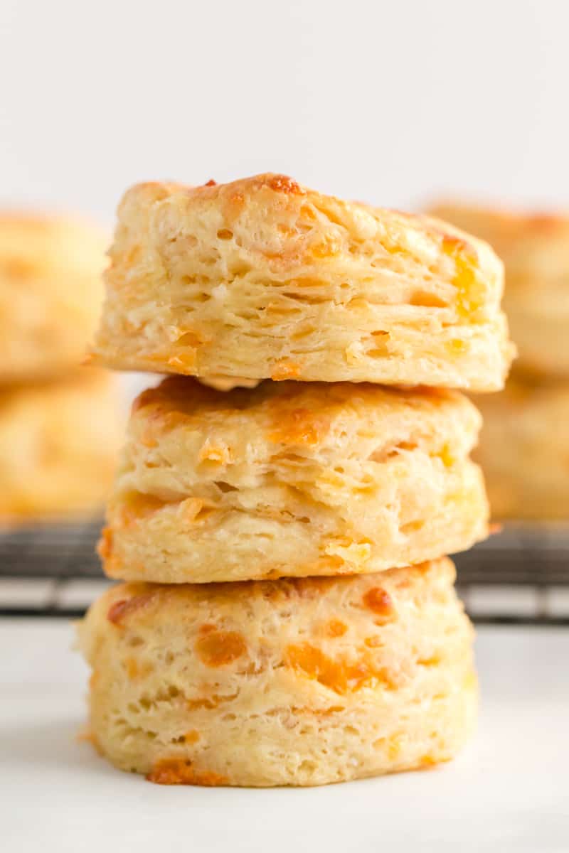 Three biscuits stacked on top of one another with biscuits on rack in background