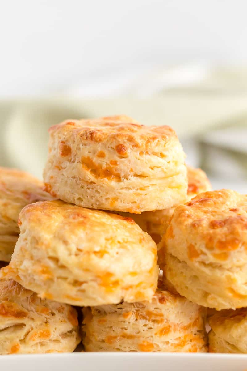 Cheddar Biscuits layered atop one another with golden tops on white platter