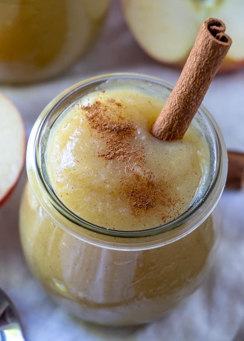 Close up photo of applesauce in jar with cinnamon sprinkle and cinnamon stick