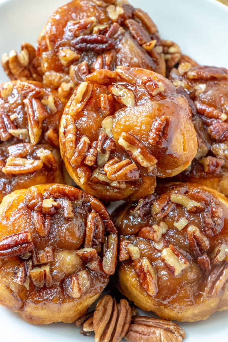 Up close photo of sticky buns stacked showing caramel glaze and pecans