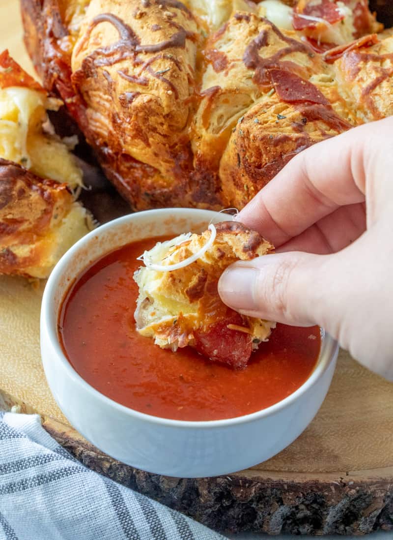 Dipping a biscuit piece into pizza sauce