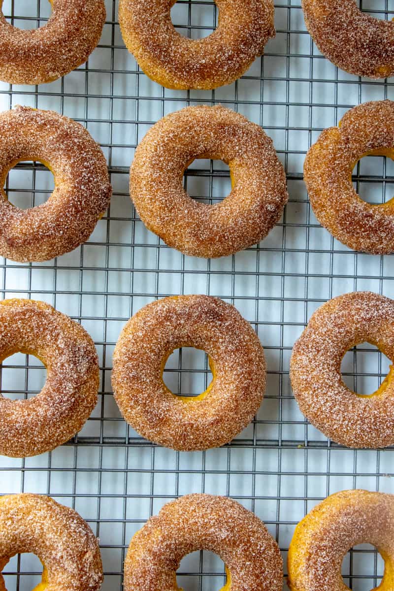 Pumpkin Donuts on cooling rack after being dipped in butter and cinnamon sugar