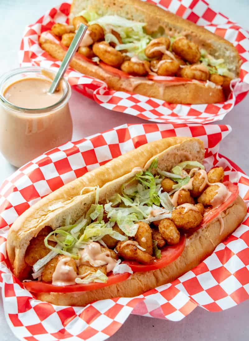 Shrimp Po' Boys in basket with checkered paper, dressed with lettuce and tomatoes