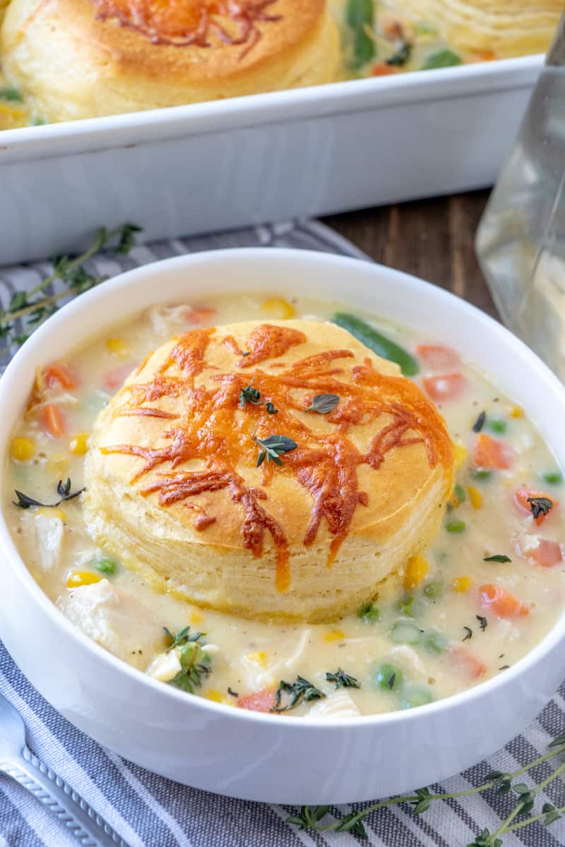 Chicken Pot Pie Casserole in bowl with biscuit on top and thyme springs around
