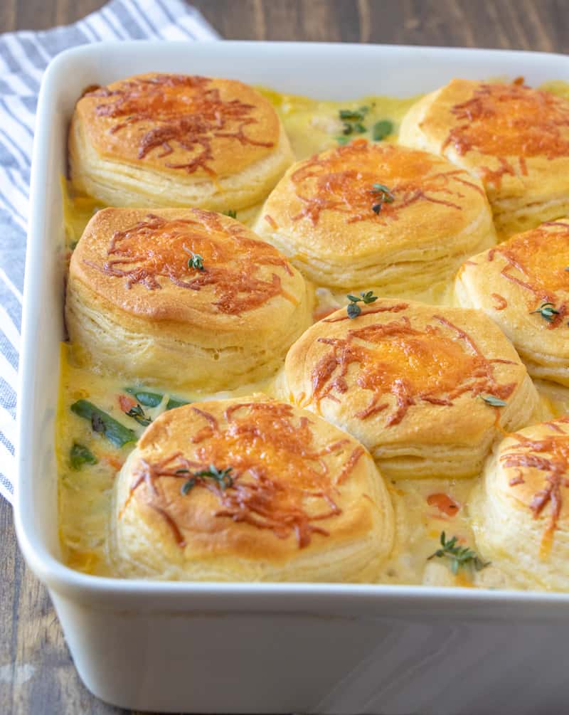 Chicken Pot Pie Casserole in baking dish with golden biscuits topped with fresh thyme leaves
