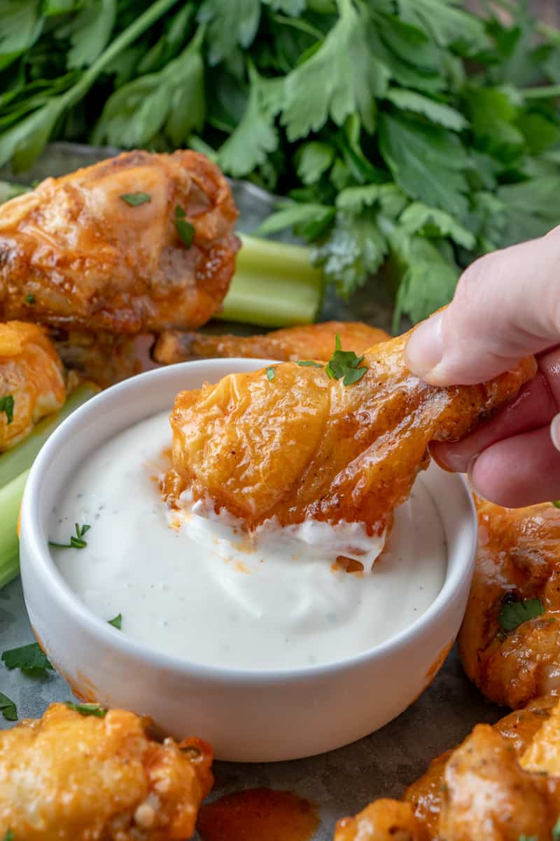Buffalo wing being dipped into ranch dressing