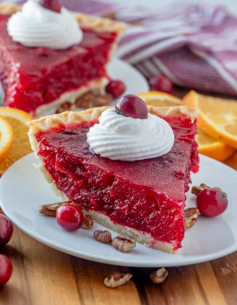 Slice of Cranberry Pie on plate topped with whipped cream and a cranberry