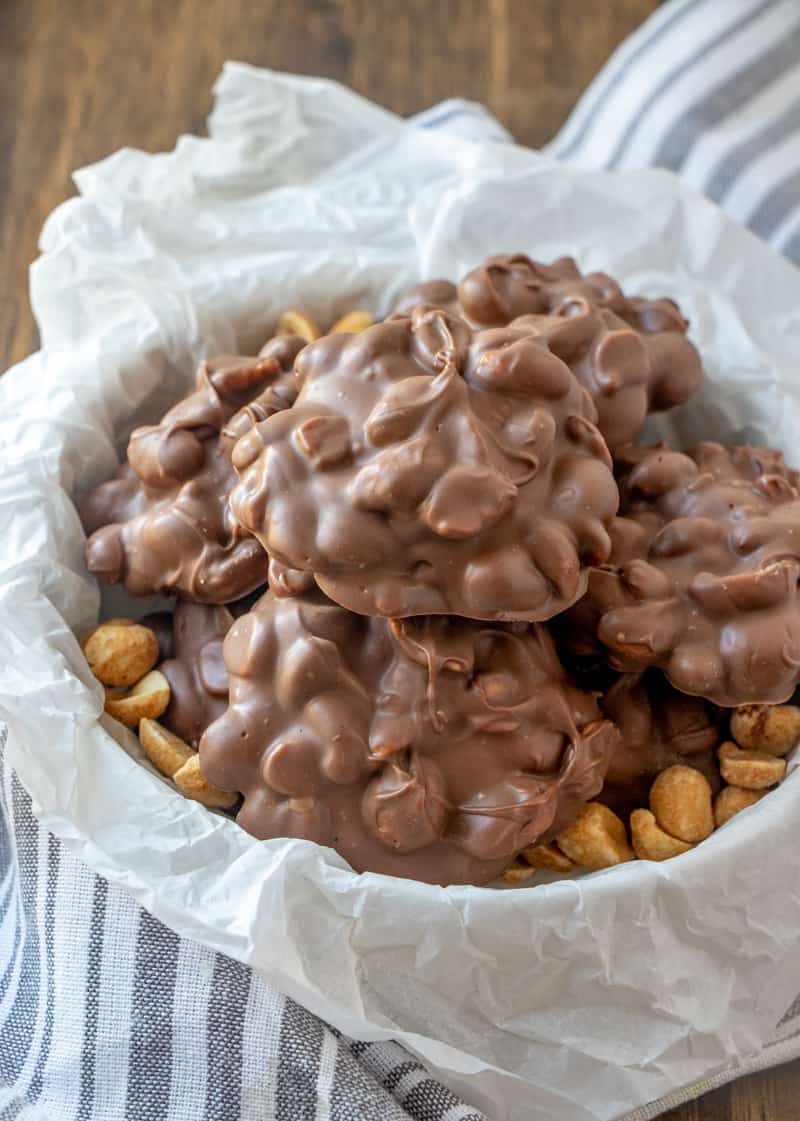 Peanut Clusters in bowl lined with parchment paper stacked on top of one another