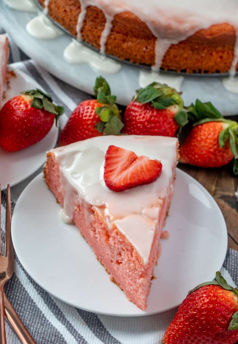 Overhead photo of slice of cake on white plate surrounded by strawberries