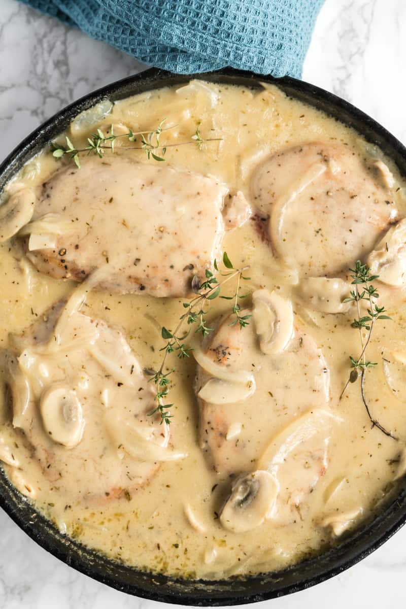 Overhead photo of pork chops in pan garnished with sprigs of thyme