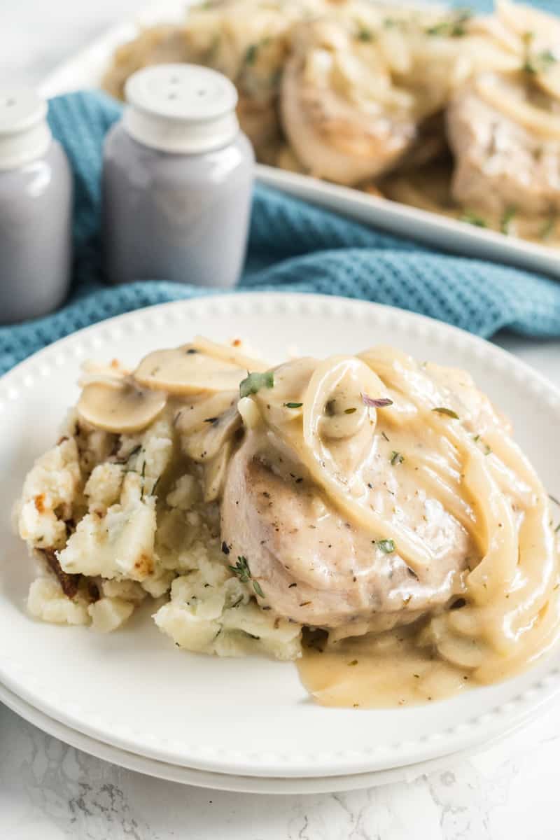 Smothered Pork Chops on plate over mashed potatoes and topped with mushroom and onion gravy