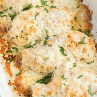 baked cheesy chicken in baking pan with parsley garnish