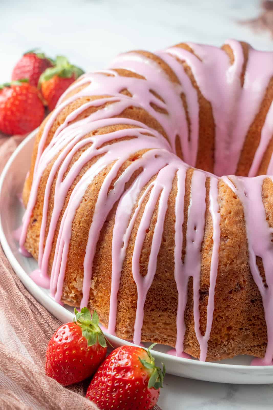 Photo of finished strawberry cake glazed on serving platter with strawberry garnish