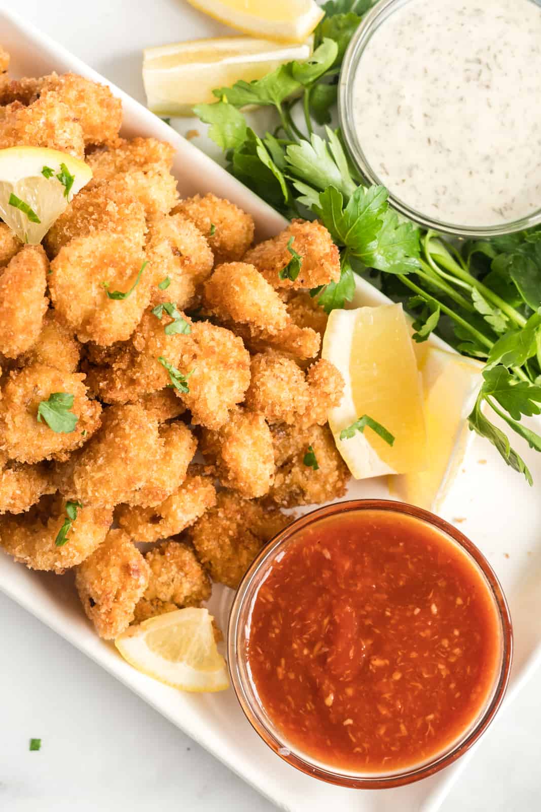 Overhead photo of shrimp on plate with cocktail sauce and slices of lemon