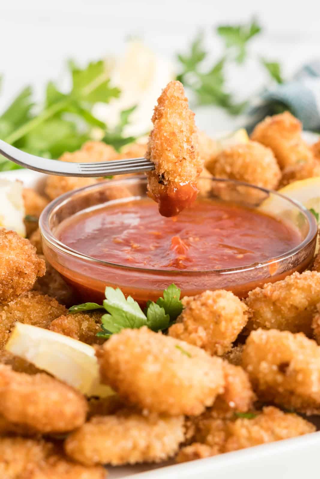 Fork dipping one shrimp in cocktail sauce