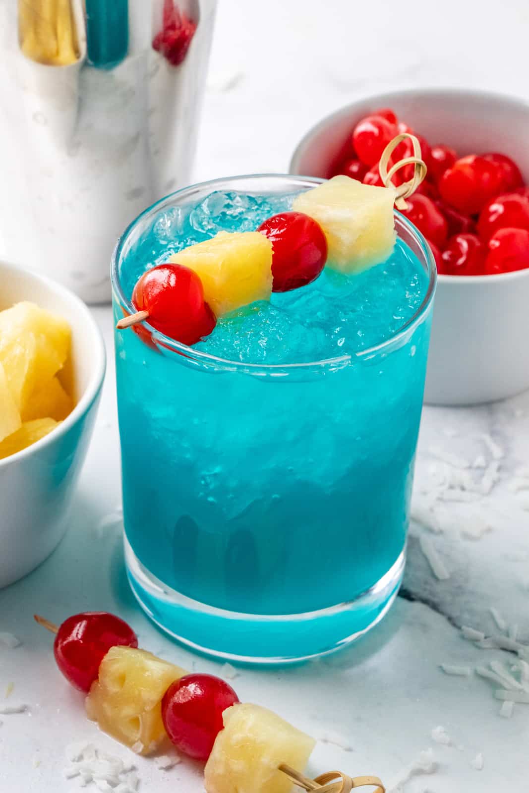 Голубой гавайский коктейль в стакане со льдом, ананасом и вишней