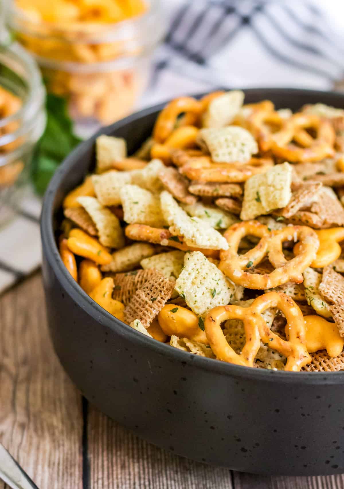 Air Fryer Ranch Chex Mix in black bowl with ranch seasoning showing on ingredients.