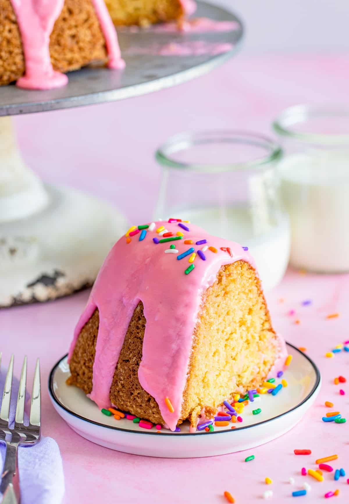 Slice of the Donut Cake on white plate with milk in backgound.