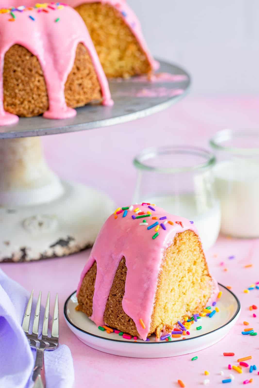 Slice of Donut Cake on plate with cake on cake stand in background