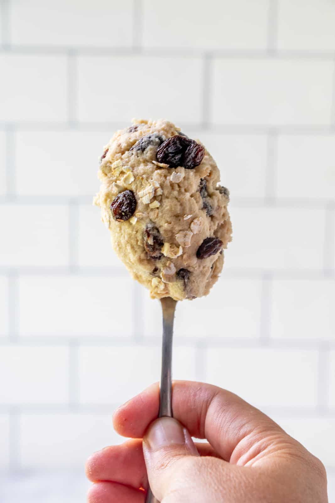 Hand holding spoon full of cookie dough