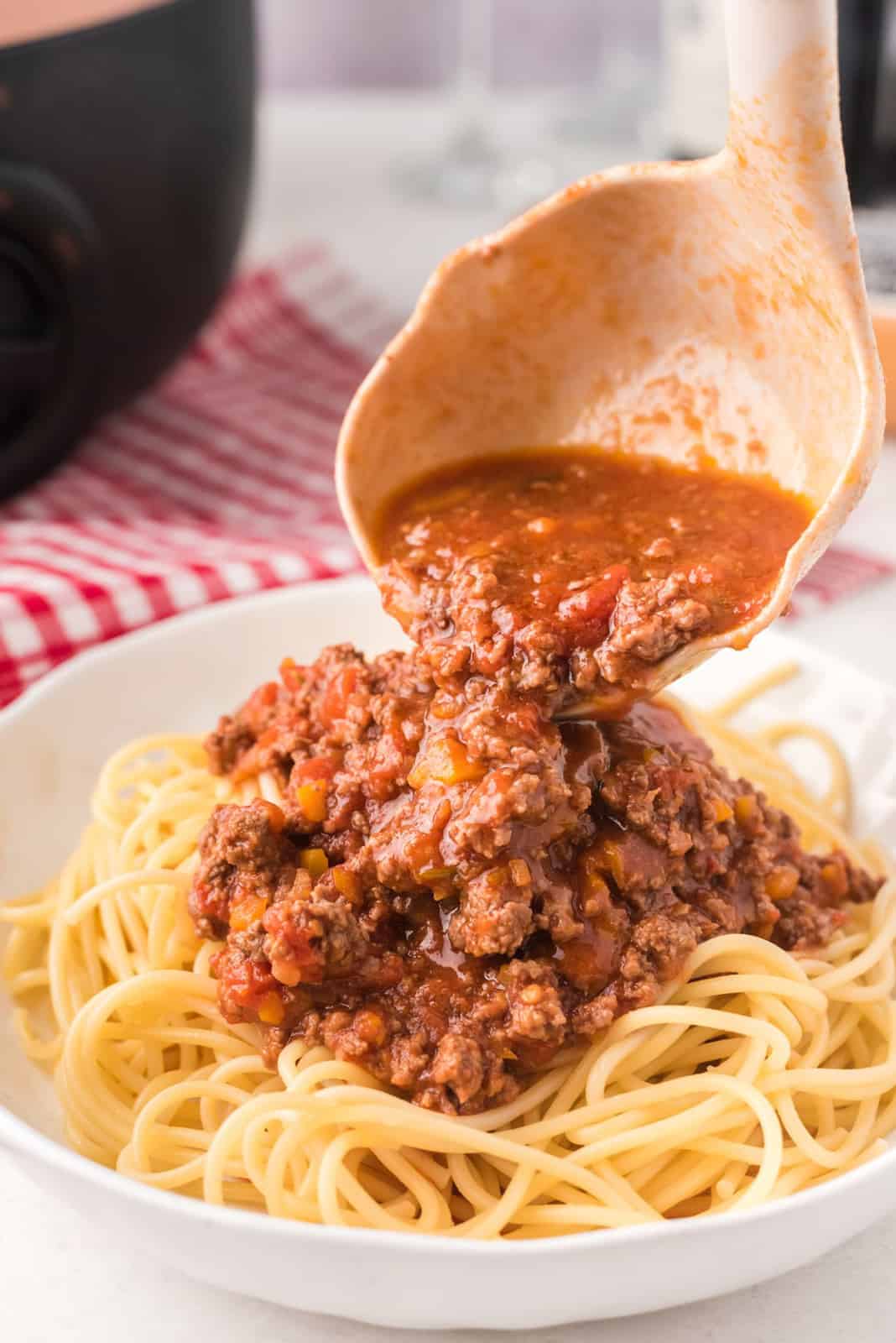 Ladle pouring Bolognese Sauce over pasta