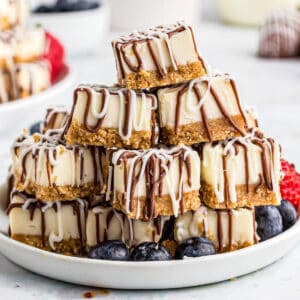 Close up square image of bites on white plate with strawberries and blueberries showing chocolate drizzle.