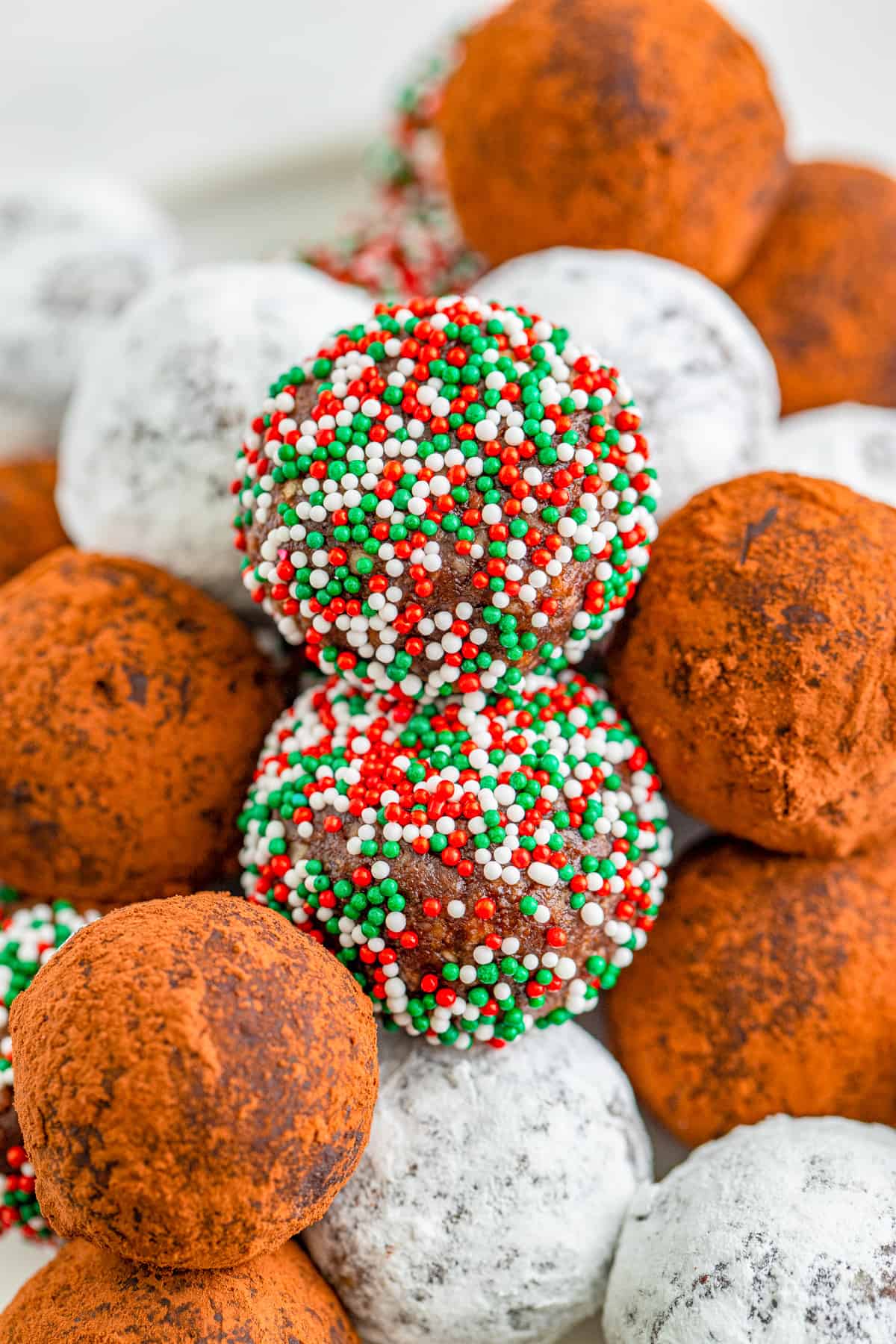 Close up of Rum Balls stacked showing all the different ingredients they are rolled in.