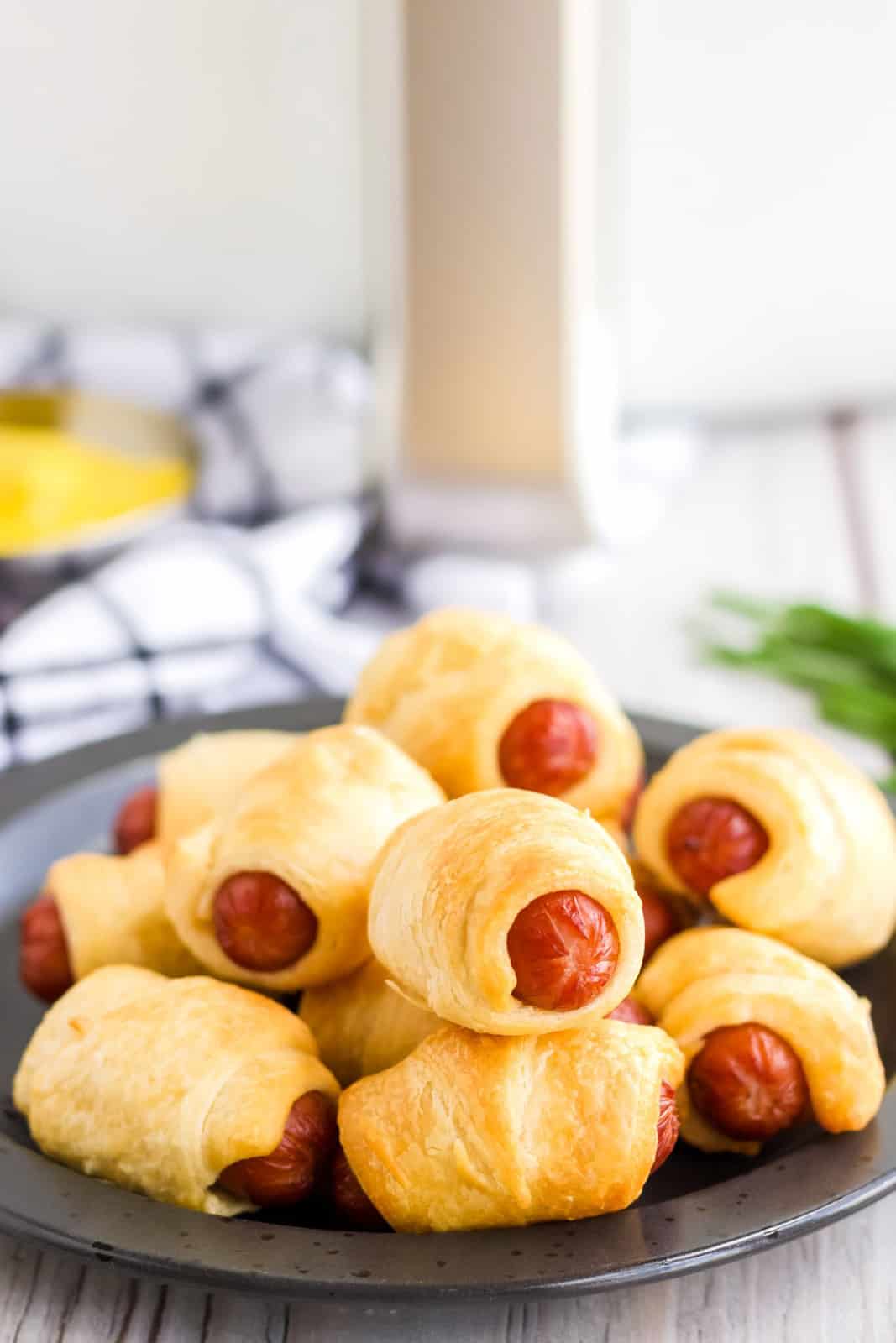 Pigs in a Blanket on black plate in front of air fryer